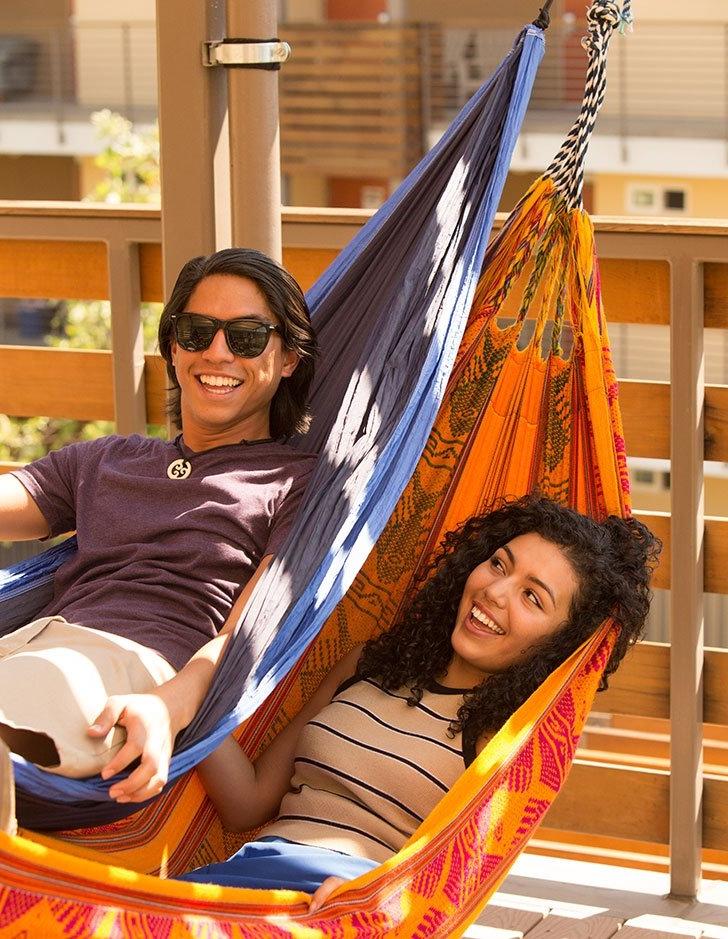 two students sit in hammocks on a balcony